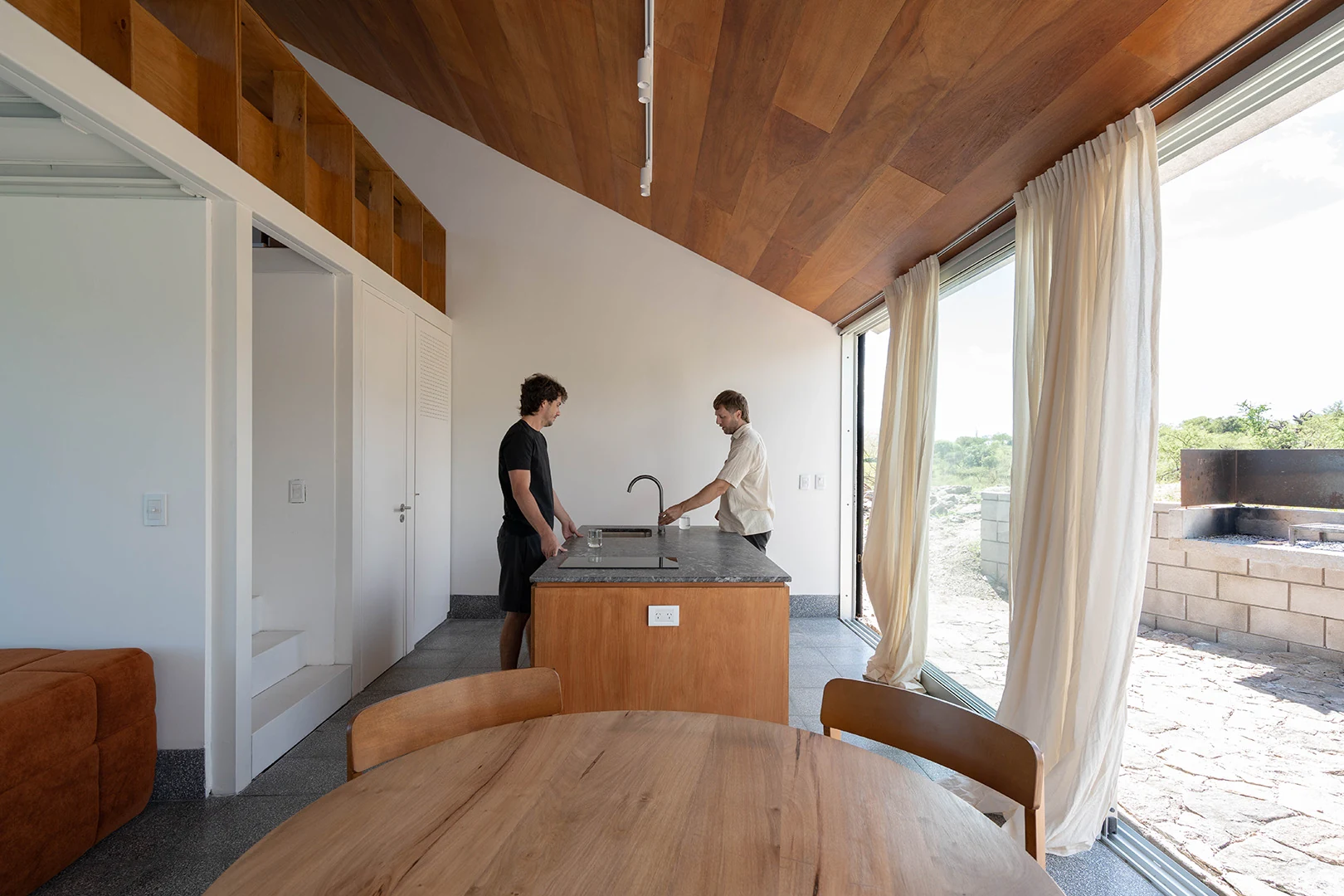 Cocina abierta del loft con mesada y alacenas de madera.