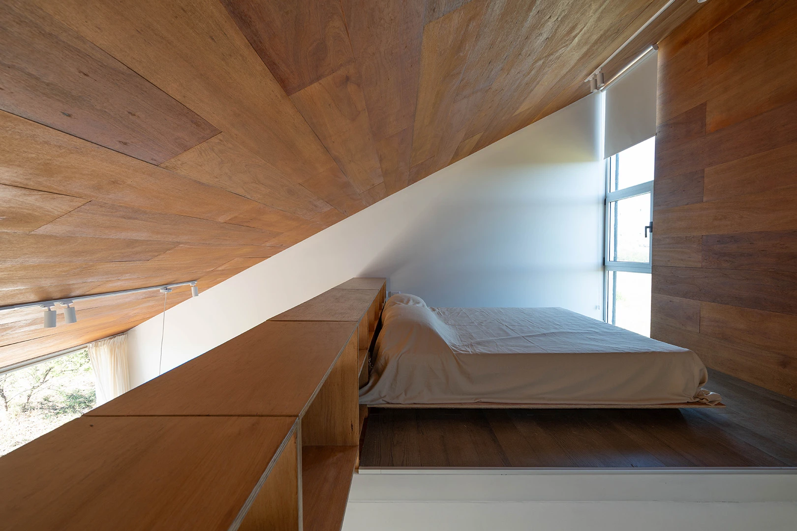 Dormitorio con techo de madera y ventana hacia el paisaje.