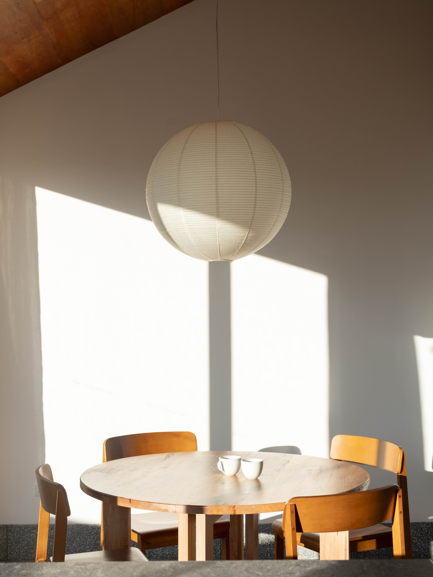 La luz del sol sobre la mesa de madera y la lámpara de papel del loft.